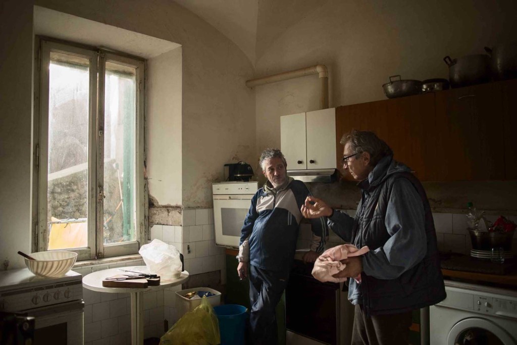Walter e Marco discutono in cucina, spazio comune dove tutti gli abitanti della Tenuta Vaselli preparano i loro pasti.